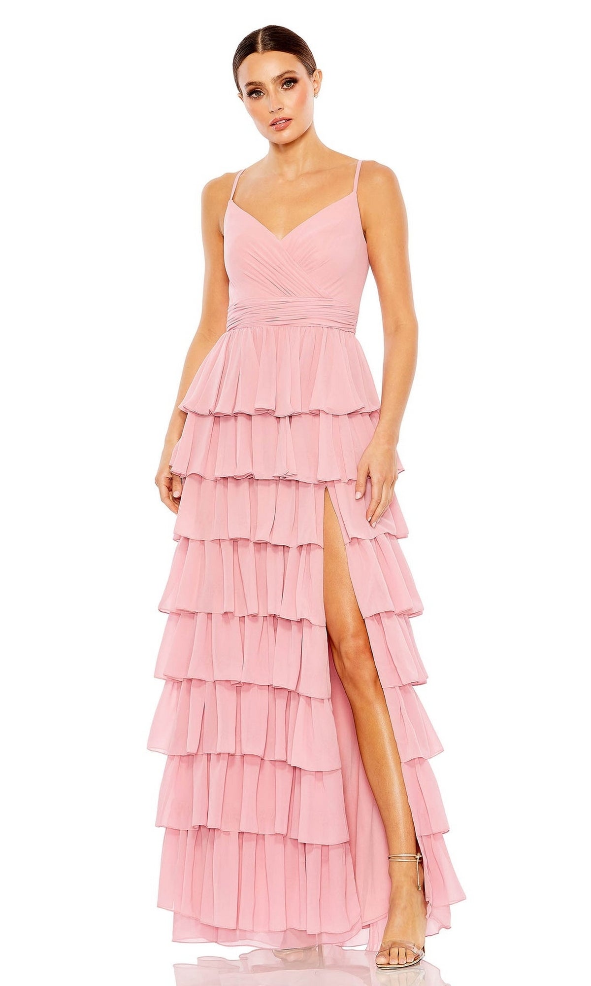A woman stands against a white background wearing the Mac Duggal 55416 Ruffled Long A-Line Prom Dress, a sleeveless light pink gown featuring a V-neckline and high slit.